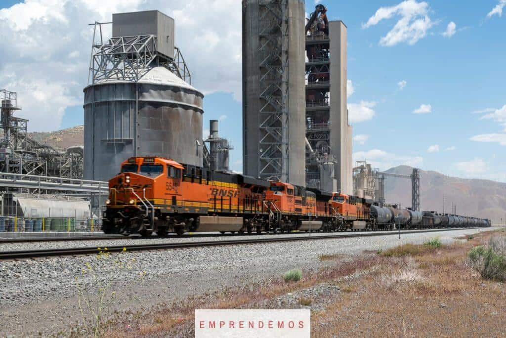 A train is traveling down the tracks near an industrial building