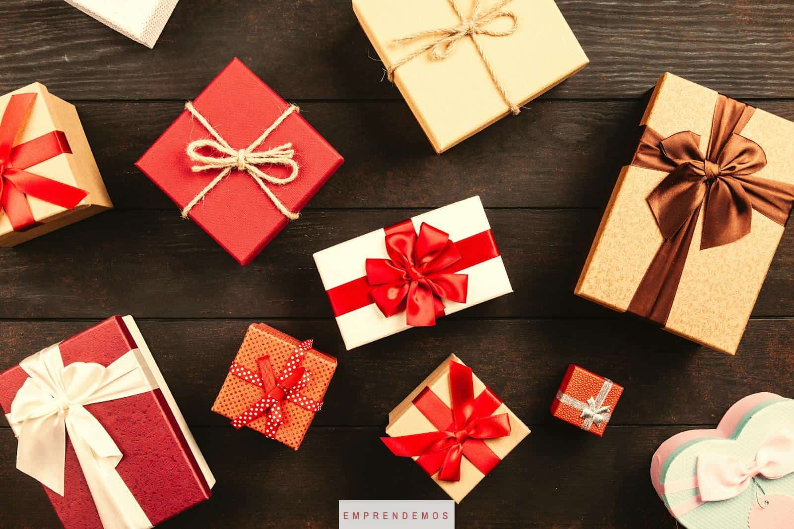 Top view of various wrapped gifts with bows on a wooden table, perfect for Christmas or celebrations.