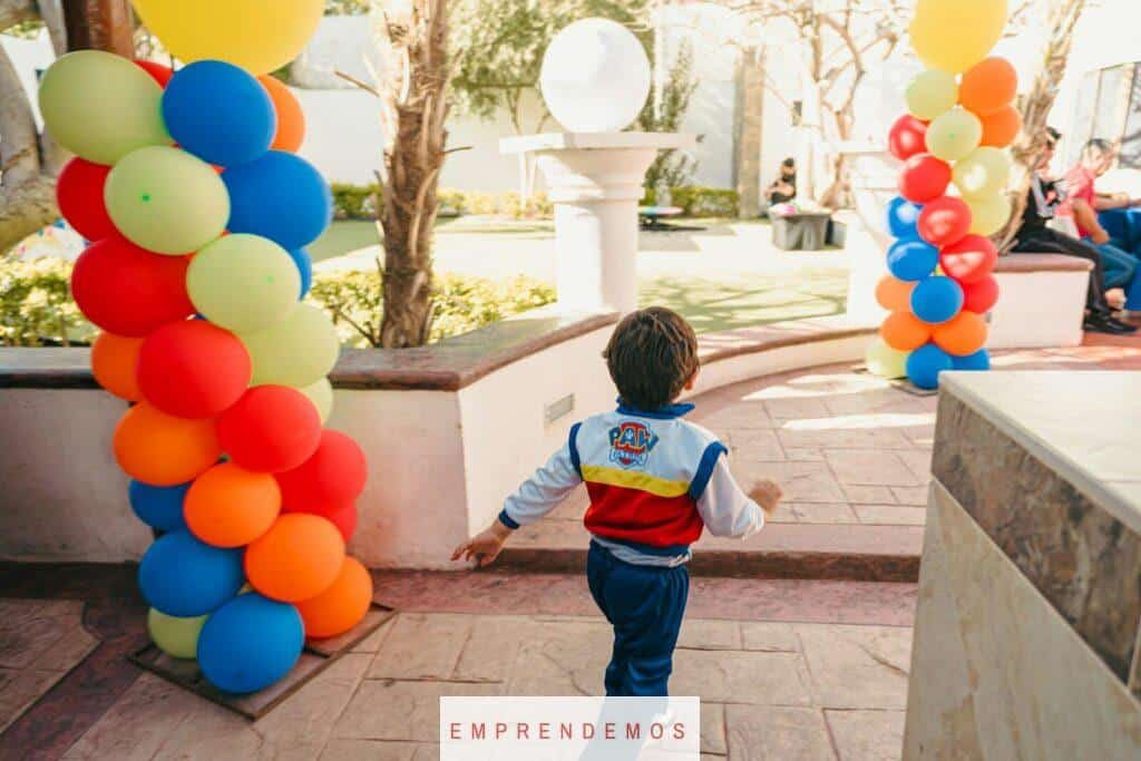 Boy in paw patrol jacket runs past colorful balloons